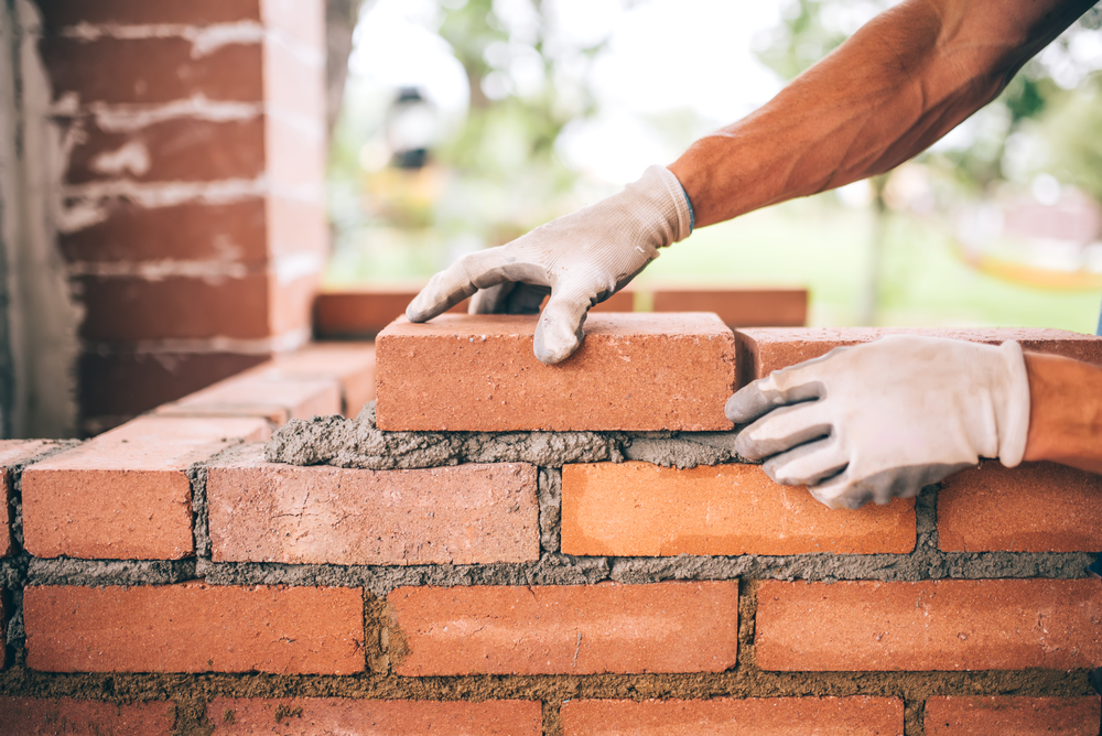 masonry installer building brick wall.